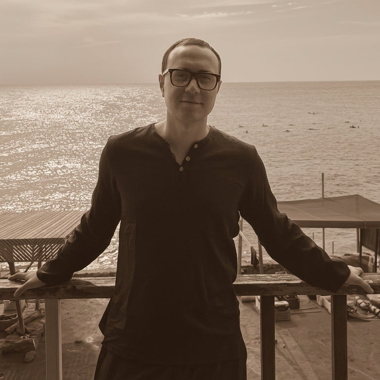 ABA'z, a man wearing black athletic apparel and glasses stands with his arms resting on the railing overlooking the sea.