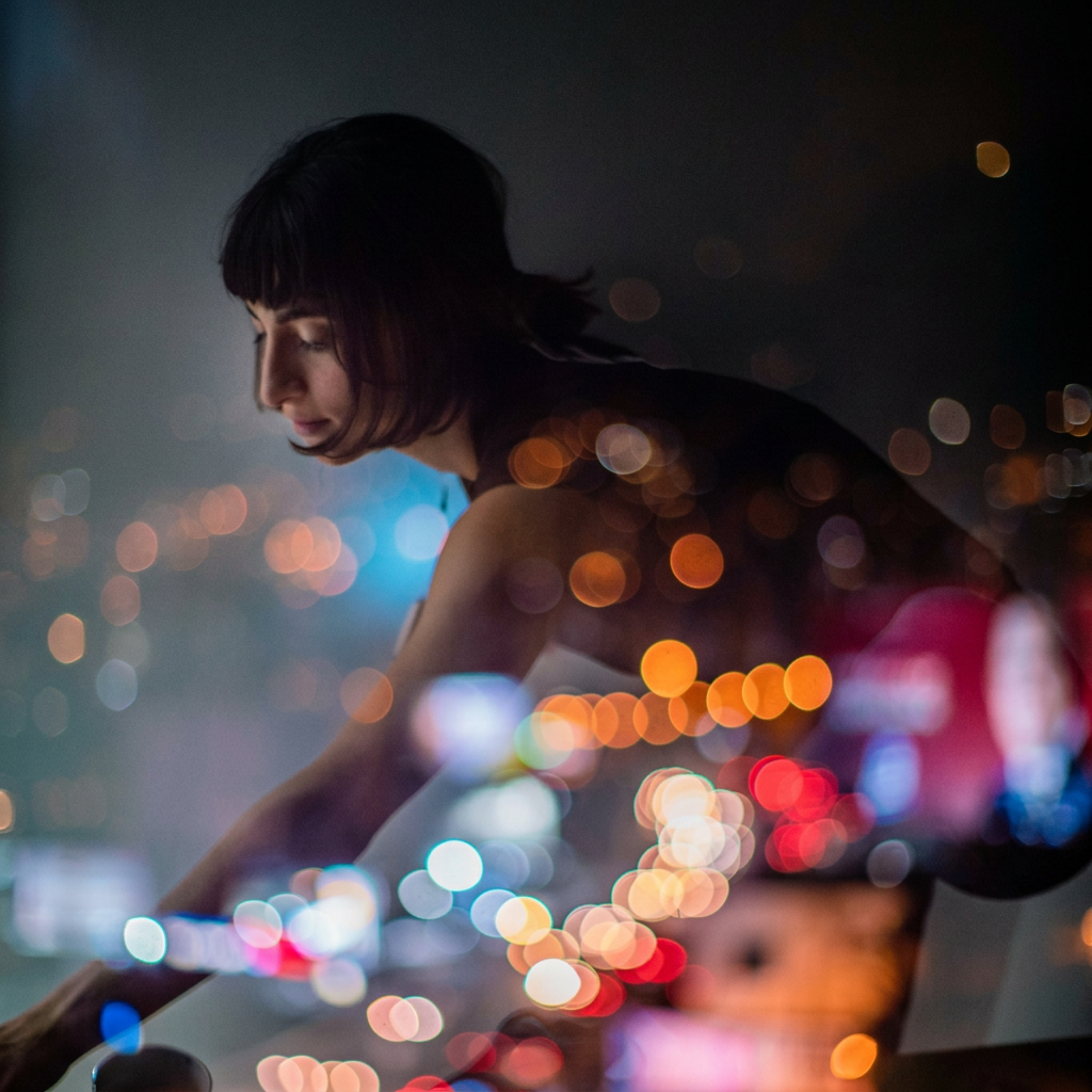 A dark, artistic lifestyle photograph of a person in silhouette against a blurred city night scene filled with colorful bokeh lights.